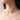 Gold necklace with heart-shaped charms on a person's neck against a neutral background